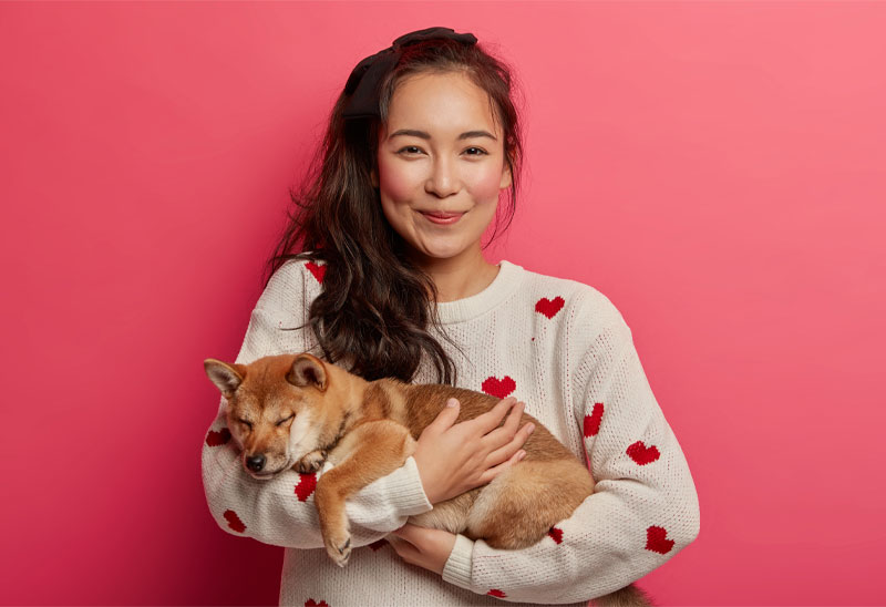 A smiling female pet owner sharing a joyful moment hugging her healthy puppy dog, representing the Dog Flea and Tick community's commitment to vet trusted protection.